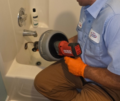 TKO Plumbing Services technician clearing a tub stoppage
